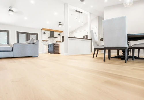 Expansive view of smooth, light-colored vinyl plank flooring flowing through a bright, open-plan living and dining area with modern furnishings and natural lighting.