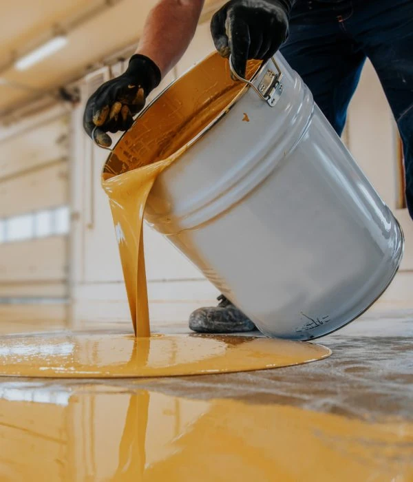 Textured surface of industrial-grade epoxy flooring granules in blue, white, and black — used for slip resistance and decorative finish in commercial or garage settings.