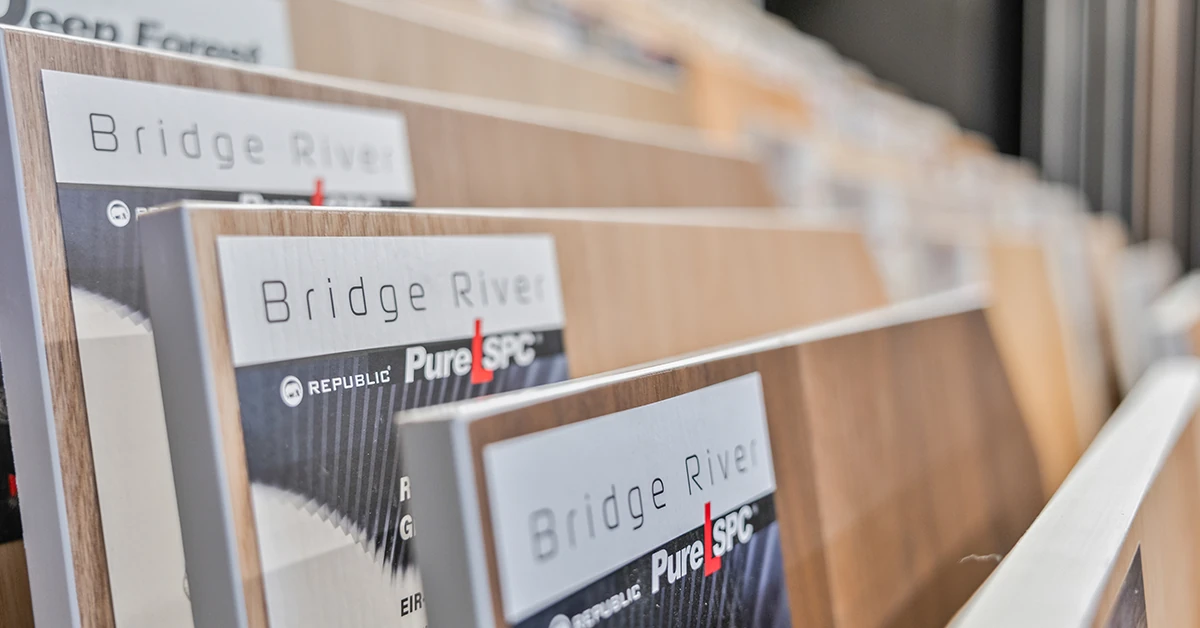 Focused shot of Republic Bridge River Pure SPC flooring swatches, showcasing realistic wood grain patterns and brand labeling to assist homeowners in choosing the perfect style.