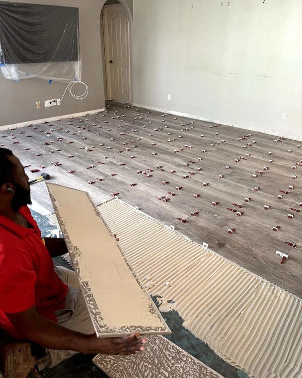 Red Eagle Flooring technician performing a precise flooring installation service using leveling clips and adhesive