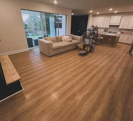 Open-concept living room and kitchen upgraded with modern wood-look vinyl flooring — get your Free Flooring Quote for seamless installs.