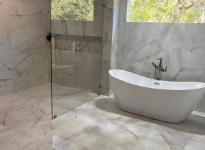 Elegant bathroom renovation featuring marble tile flooring and a freestanding tub — ask Red Eagle Flooring for your Free Flooring Quote.