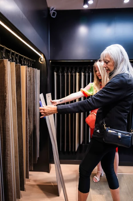 A woman and young girl examining wood-look flooring samples together in the Red Eagle Flooring showroom, selecting the perfect style for their home.