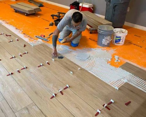 Red Eagle installers applying floor with precision leveling tools — book your Free Flooring Quote for expert tile installation.
