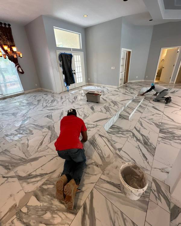 Flooring installation services expert applying large marble tiles in a spacious open-concept living area