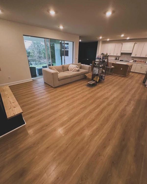 Open-concept living room and kitchen upgraded with modern wood-look vinyl flooring — get your Free Flooring Quote for seamless installs.
