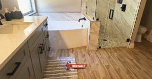 A modern bathroom with wood-look tile flooring and marble accents, ideal as pet-friendly flooring due to its water resistance and easy cleaning. 