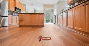Classic kitchen design featuring warm, reddish wood cabinetry and seamless wood-look Kitchen and Bathroom Flooring extending toward the living area.