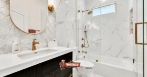 Luxurious bathroom remodel showcasing marble-look tile Kitchen and Bathroom Flooring and walls, complemented by a black vanity, gold fixtures, and an arabesque accent tile.
