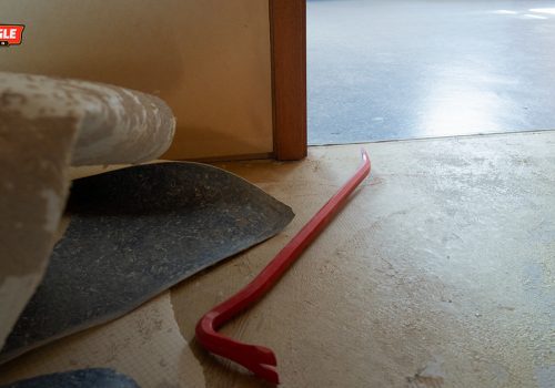 Close-up of old flooring being removed with a crowbar during a flooring renovation project
