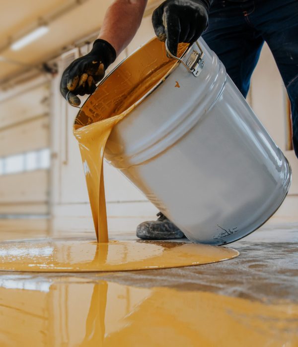 Closeup shot of a construction worker pouring out epoxy resin from a bucket onto a floor A closeup shot of a construction worker pouring out epoxy resin from a bucket onto a floor