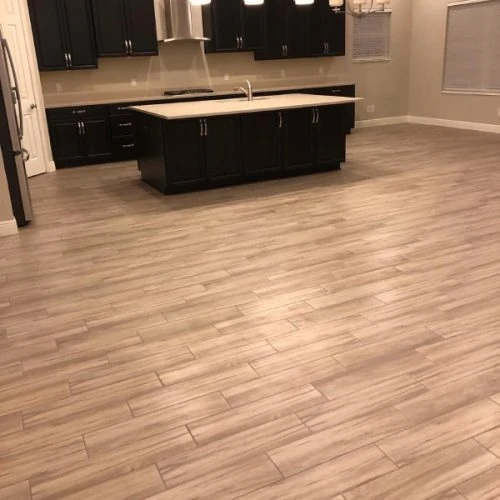 Spacious kitchen with light wood-look tile flooring — modern flooring installation service by Red Eagle Flooring