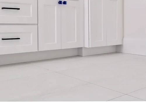 Detailed view of elegant white tile flooring beneath sleek white kitchen cabinets, emphasizing clean lines and a polished finish.