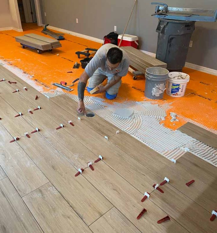 A professional tiler installing planks for the flooring